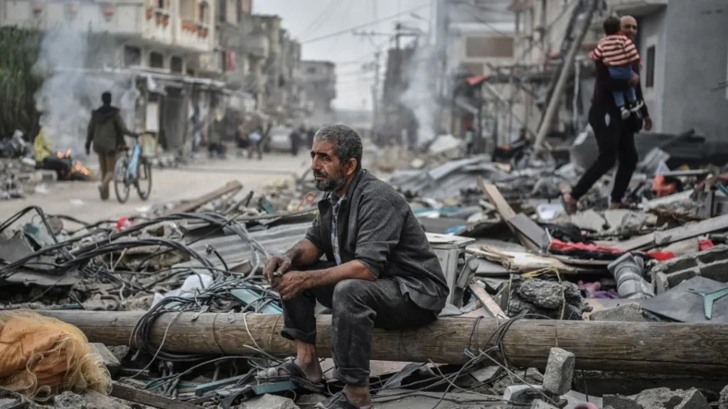 إيرلندا: ما يعانيه سكان غزة "مروع وغير إنساني" 3 Man in Gaza sits among destroyed buildings